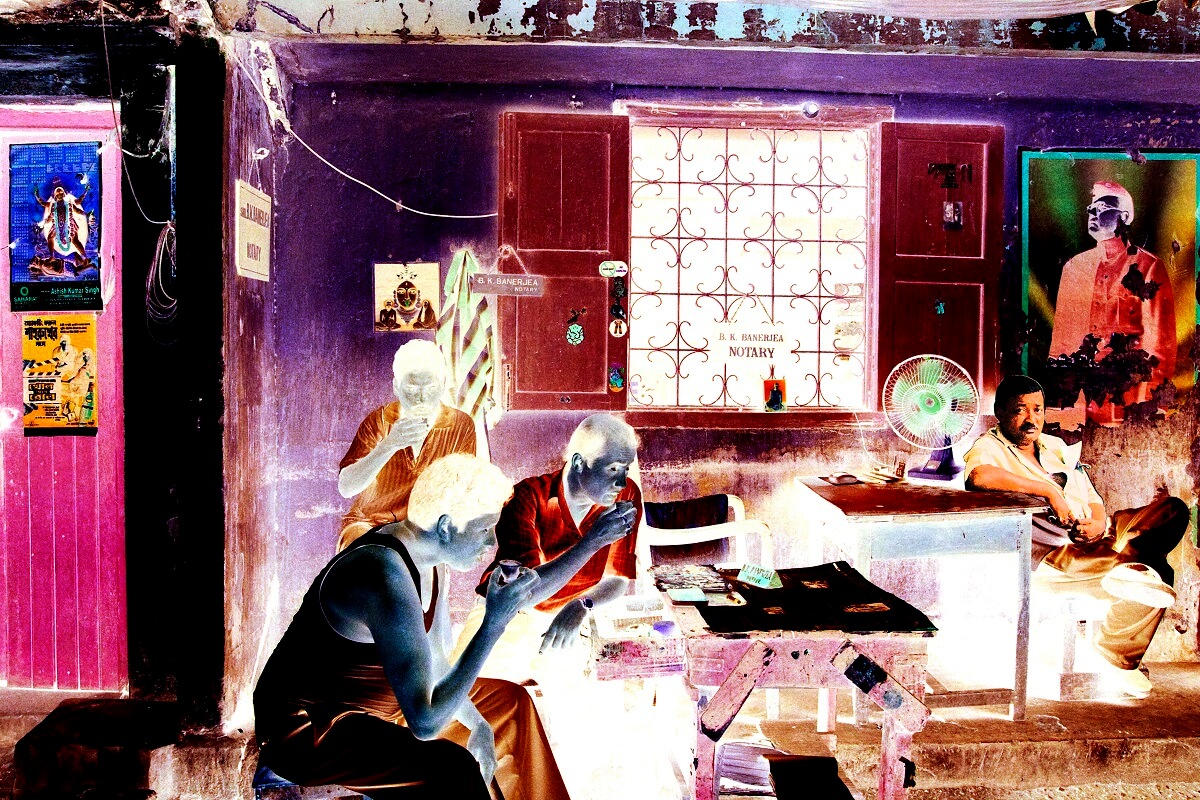 A negative-filtered image of a notary office where three men drink tea, while another reclines near a desk with papers