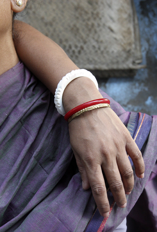 Close-up of a woman's hand adorned with traditional bangles, resting on another person's shoulder