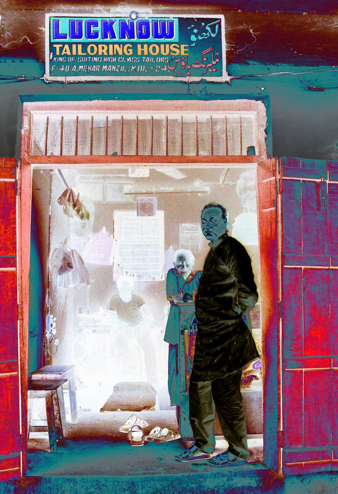 A negative image of a Babu standing in front of a tailoring shop, with shades of grey coaxing the details within