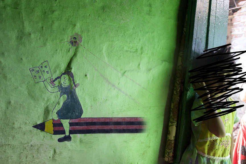 A green wall features a painted illustration of a girl reading on a pencil, while a child in a dress stands partially in the doorway