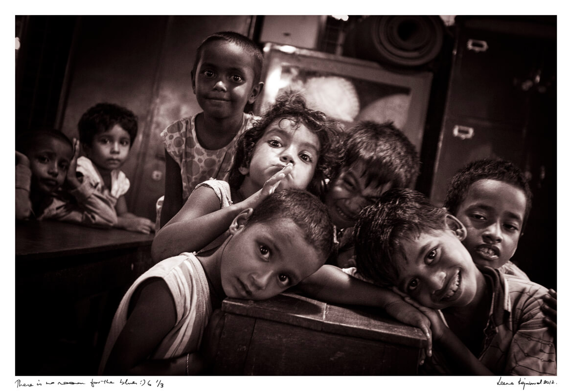 Inside a night shelter, children sit close, their smiles radiant—echoes of joy in an unlikely place