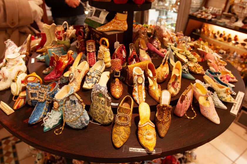 A display of miniature decorative shoes with intricate designs and vibrant colors, arranged on a wooden circular shelf