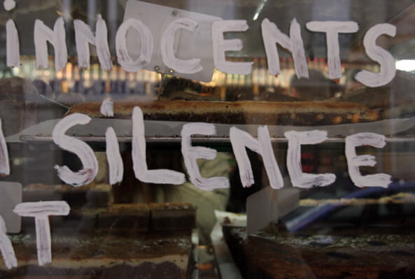A bakery display case with baked goods, featuring "INNOCENTS SILENCE" painted in white on the glass