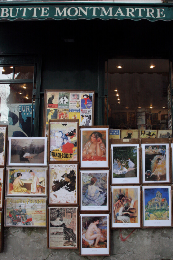 An outdoor display at "Butte Montmartre" showcases vintage posters and artwork, with framed prints arranged neatly